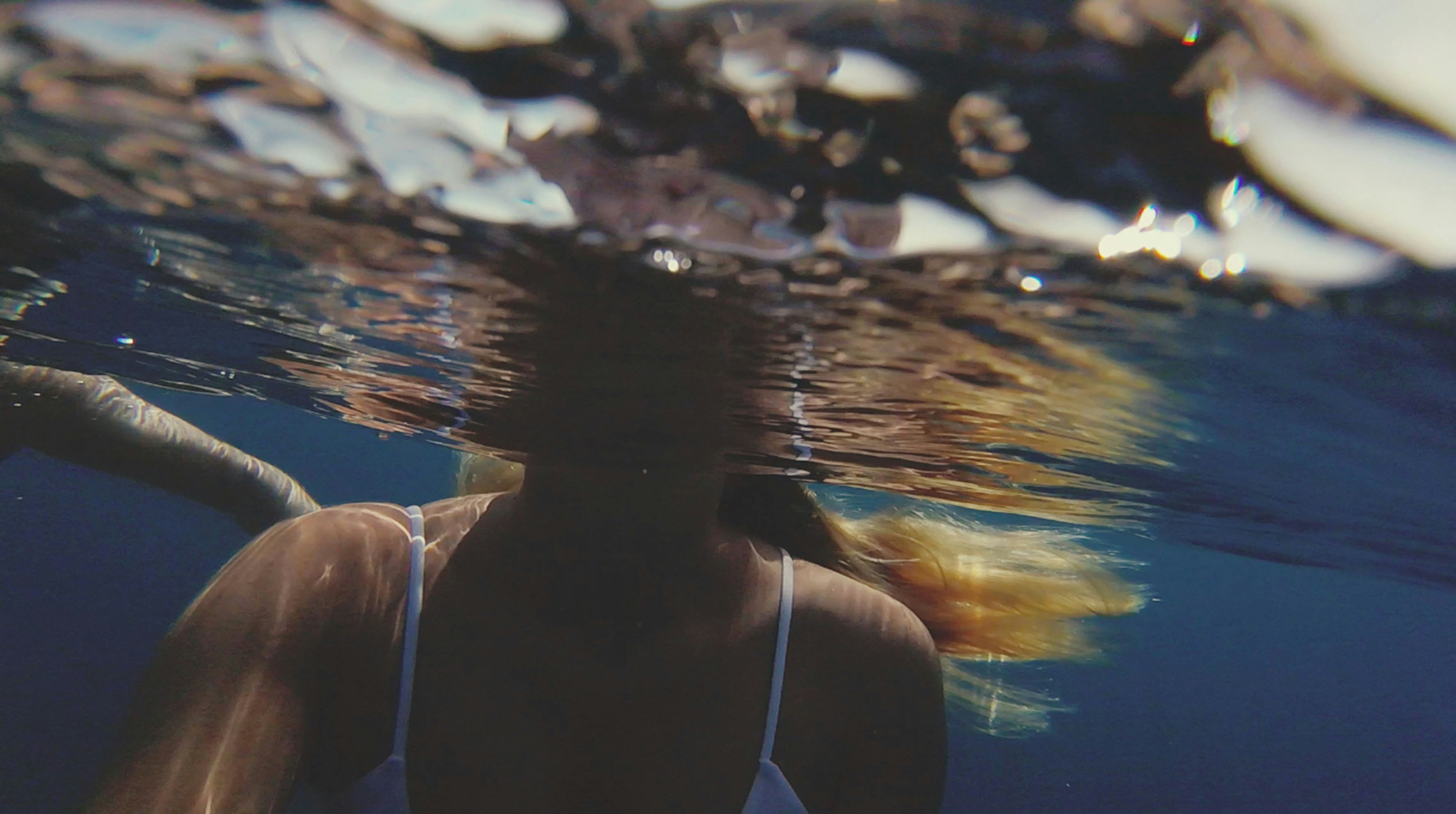 woman underwater wearing white tank top